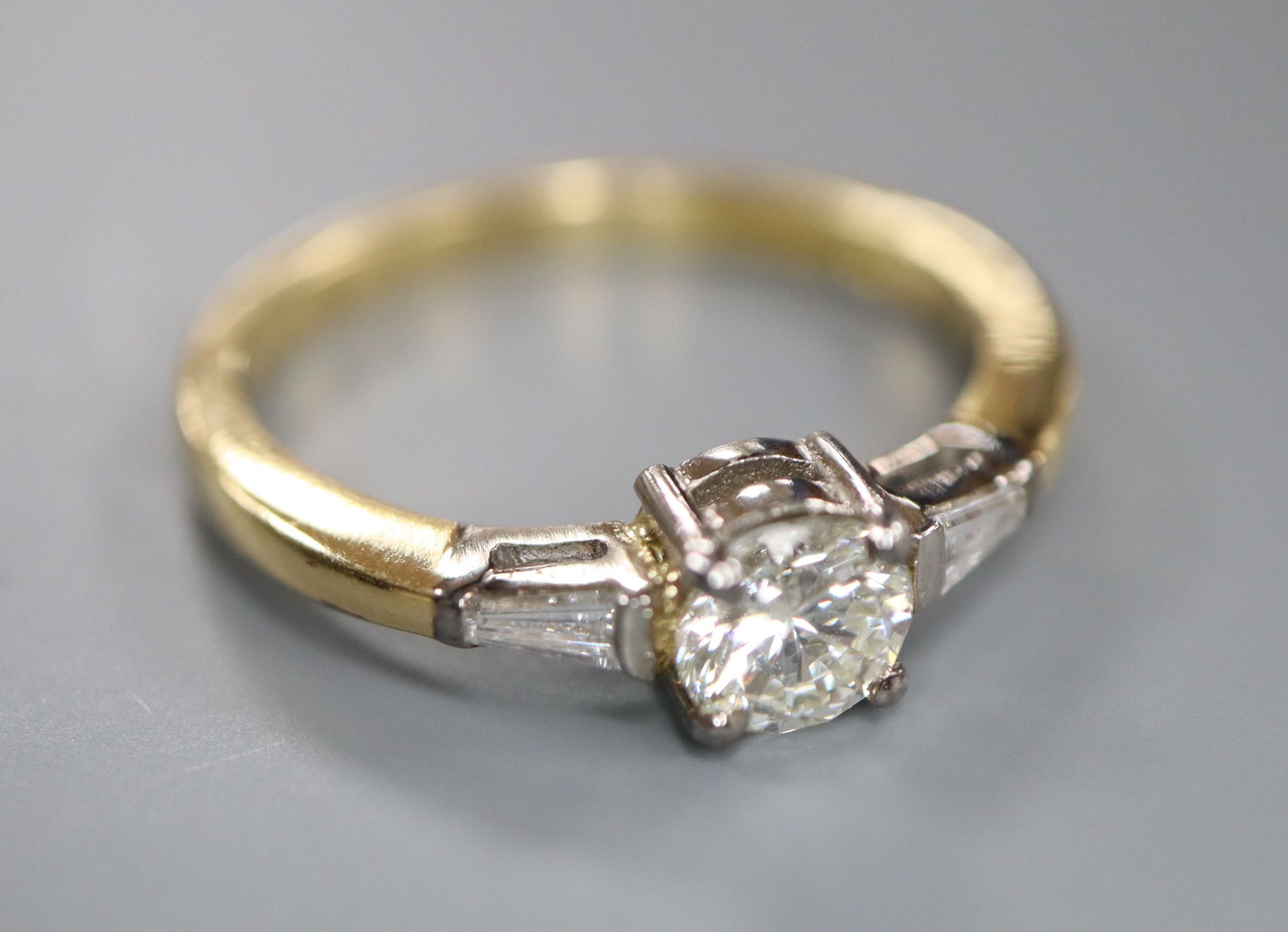 A modern 18ct gold and single stone diamond ring, with trapeze cut diamond set shoulders, size O, gross 3.7 grams,